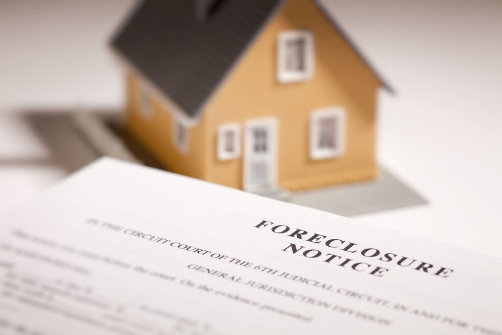 Model house resting on a foreclosure notice document