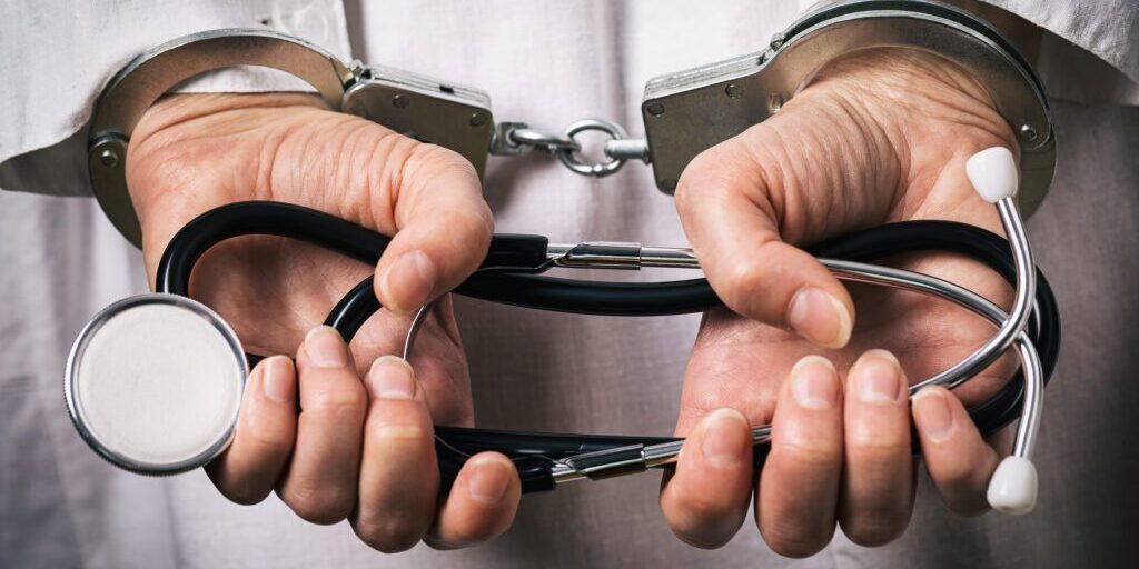 Handcuffed doctor. Medical crime concept, closeup