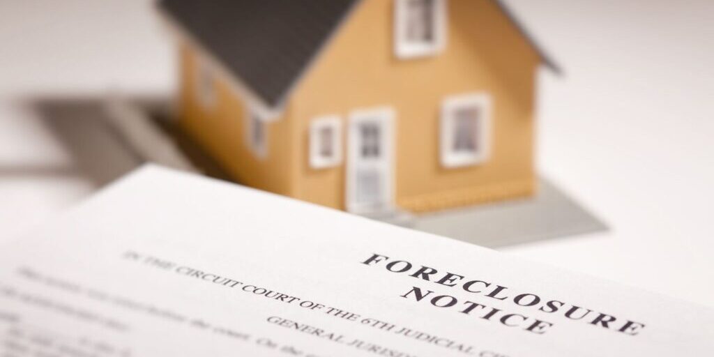 Model house resting on a foreclosure notice document