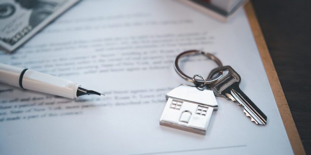 House-shaped keyring and keys resting on a signed property deed